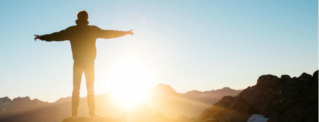 man on top of mountain watching sun
